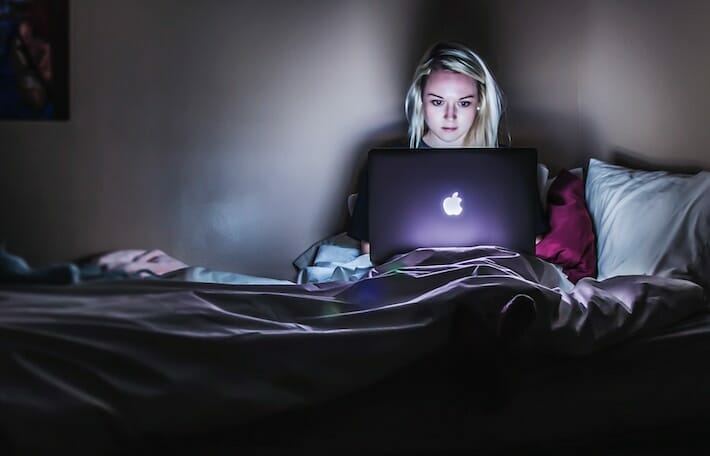 A viewer consuming media on her bed. 