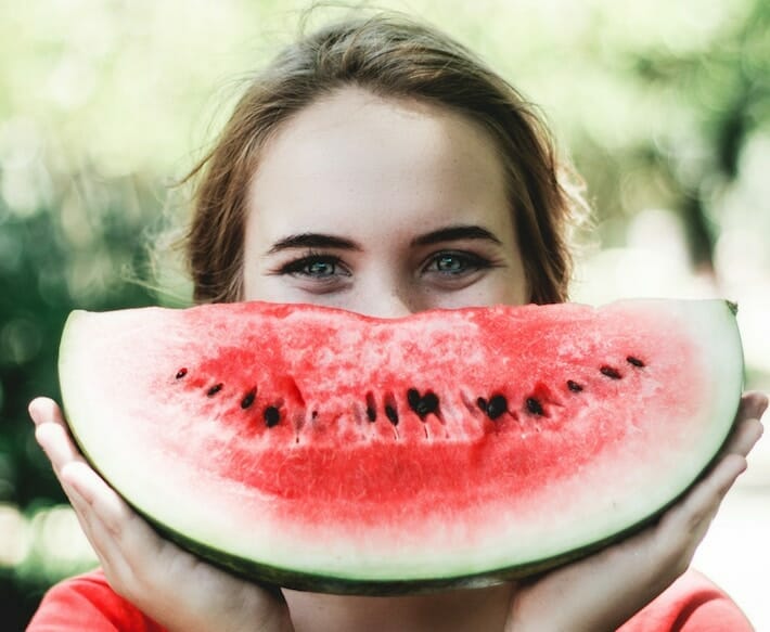 Girl with a big piece of watermelon mimicking her smile