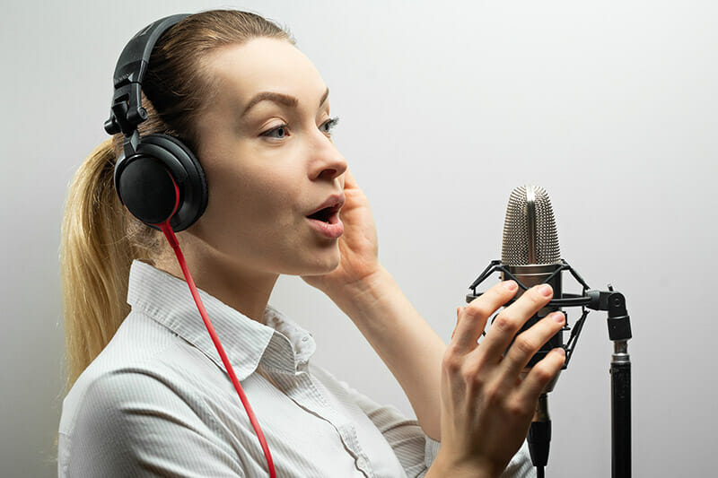 Woman doing a voice over in sound booth.