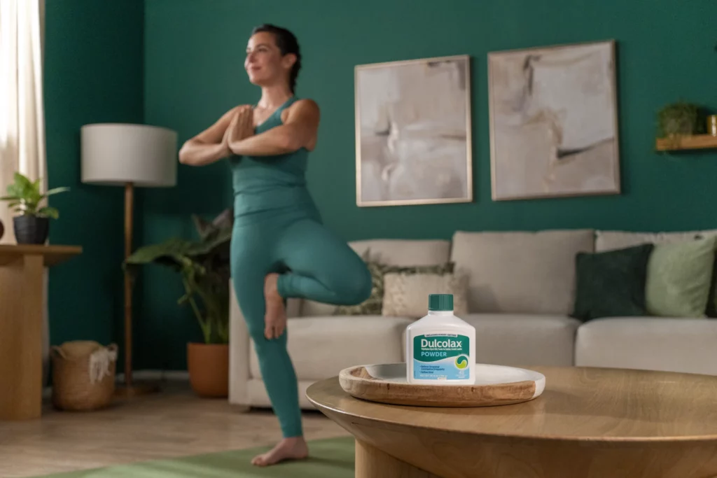 A woman practices yoga in a living room. A bottle of Dulcolax Powder sits on a tray in the foreground.
